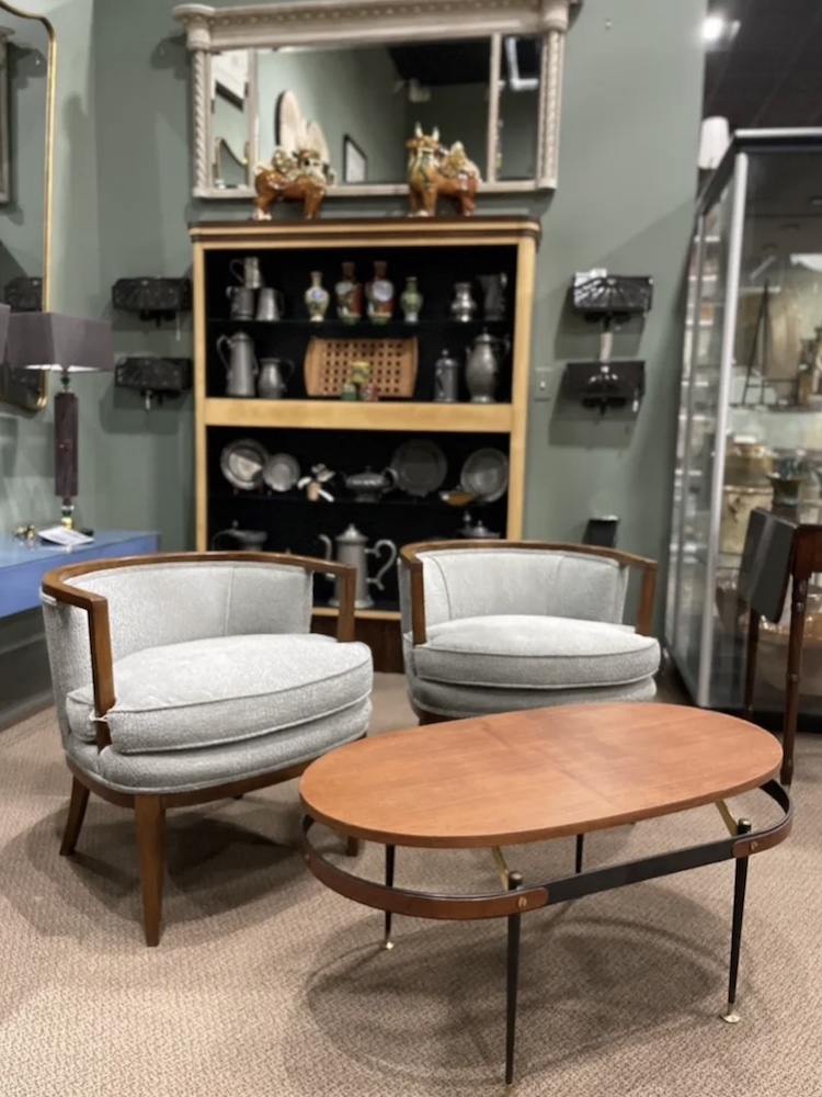 A pair of vintage walnut armchairs with low backs and a curvy profile complement a smaller scale Italian coffee table that has similar wood tones and lines.

Scott Sprague Photography/Judy Frankel Antiques